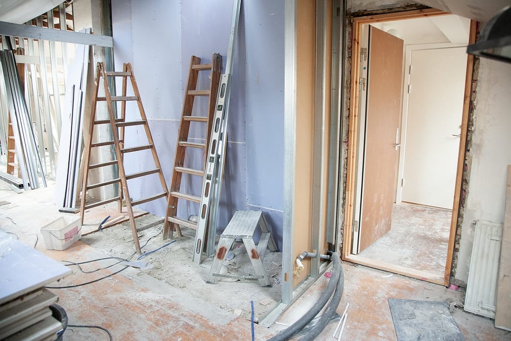 A room that is stripped and ready for drywall. Ladders rest against the light purple wall.